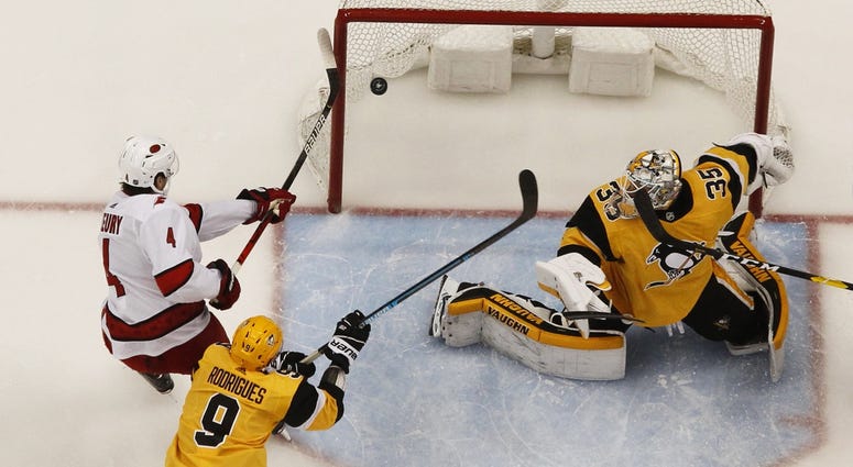Carolina Hurricanes defenseman Haydn Fleury (4) attempts to tip the puck past Pittsburgh Penguins goaltender Tristan Jarry (35) as Pens center Evan Rodrigues (9) defends during the second period at PP...