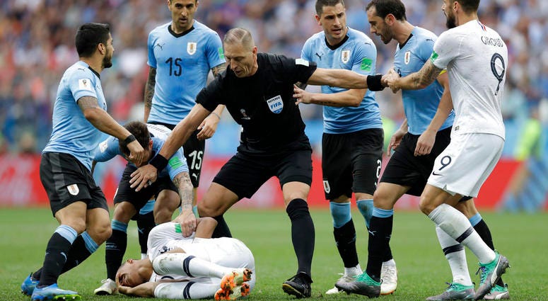 Uruguay players protest to referee Nestor Pitana of Argentina that France's Kylian Mbappe, on the ground, is overreacting after taking a dive during the quarterfinal match between Uruguay and France at the 2018 soccer World Cup DO NOT USE