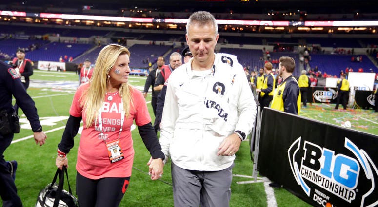 Ohio State head coach Urban Meyer walks off the field with his wife, Shelley Meyer, early Sunday, Dec. 2, 2018, after defeating Northwestern in the Big Ten championship NCAA college football game in Indianapolis. Ohio State won 45-24. DO NOT USE