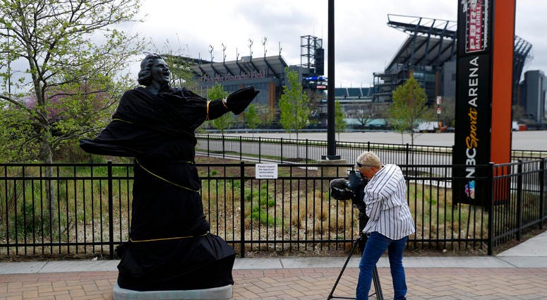 A television photographer records the partially covered statue of singer Kate Smith near the Wells Fargo Center, Friday, April 19, 2019, in Philadelphia. AP DO NOT USE