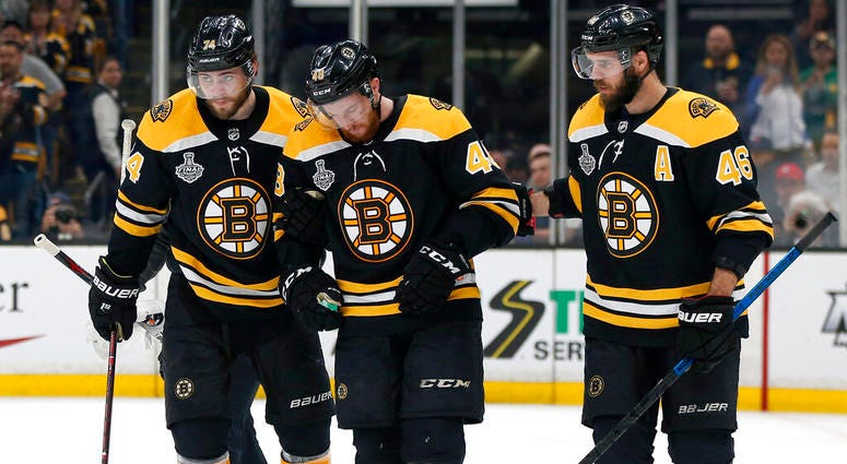 Boston Bruins' Matt Grzelcyk, center, is assisted from the ice by Jake DeBrusk, left, and David Krejci, right, after an injury during the first period in Game 2 of the NHL hockey Stanley Cup Final against the St. Louis Blues AP DO NOT USE