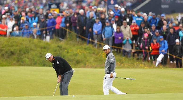 Northern Ireland's Graeme McDowell, left putts on the 14th green watched by Xander Schauffele of the United States during the first round of the British Open Golf Championships at Royal Portrush in Northern Ireland, Thursday, July 18, 2019.