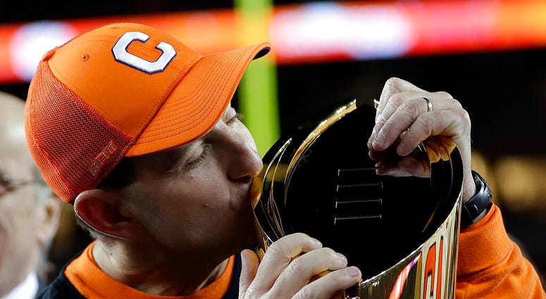 FILE - In this Jan. 7, 2019, file photo, Clemson head coach Dabo Swinney kisses the championship trophy after the NCAA college football playoff championship game against Alabama in Santa Clara, Calif.