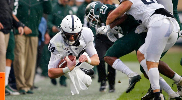 Penn State quarterback Sean Clifford, left, dives for a first down against Michigan State's Shakur Brown (29) during the first quarter of an NCAA college football game, Saturday, Oct. 26, 2019, in East Lansing, Mich.