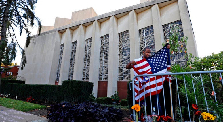 A man places an American flag outside the Tree of Life synagogue in Pittsburgh on Sunday, Oct. 27, 2019, the first anniversary of the shooting at the synagogue that killed 11 worshippers. AP DO NOT USE
