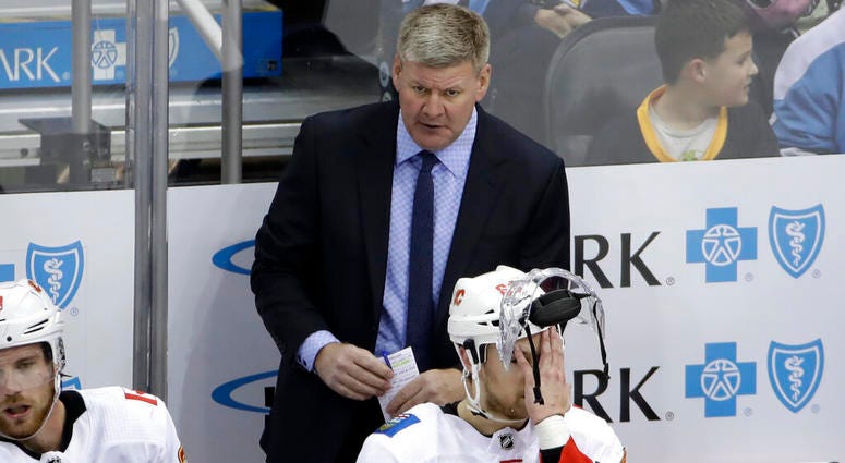 Calgary Flames head coach Bill Peters stands behind Andrew Mangiapane (88) during the third period of an NHL hockey game against the Pittsburgh Penguins in Pittsburgh, Monday, Nov. 25, 2019. The Penguins won in overtime 3-2 AP DO NOT USE