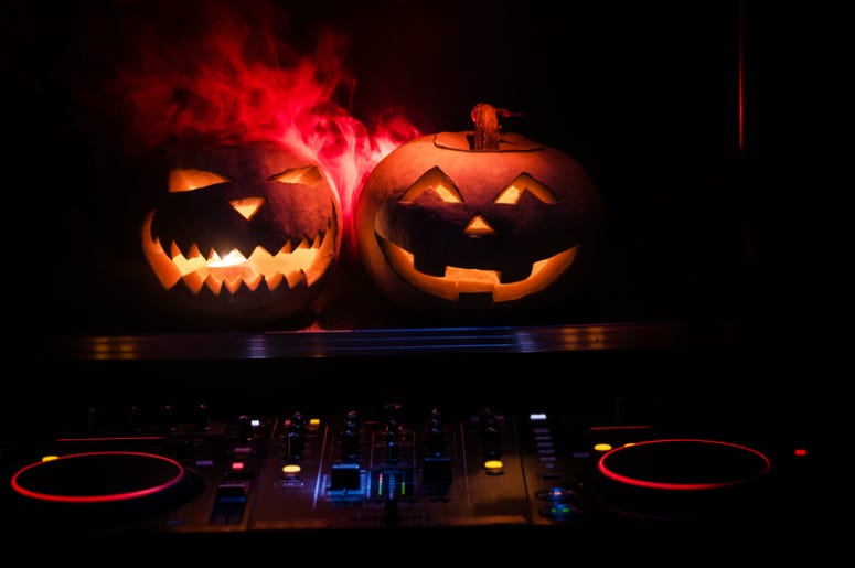 Halloween pumpkin on a dj table with headphones on dark background with copy space. Happy Halloween festival decorations and music. Halloween pumpkin on a dj table with headphones on dark background with copy space. Happy Halloween festival decorations and music.