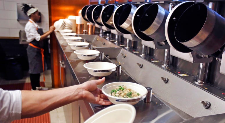 A worker lifts a lunch bowl off the production line at Spyce, a restaurant which uses a robotic cooking process, in Boston, Thursday, May 3, 2018. A worker lifts a lunch bowl off the production line at Spyce, a restaurant which uses a robotic cooking process, in Boston, Thursday, May 3, 2018.