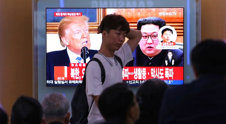 People watch a TV screen showing file footage of U.S. President Donald Trump, left, and North Korean leader Kim Jong Un.