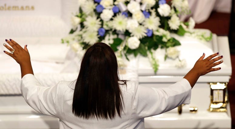 Tia Coleman stands during a musical selection during a funeral for her husband, Glenn Coleman and children, Reece Coleman, Evan Coleman and Arya Coleman, Friday, July 27, 2018, in Indianapolis.