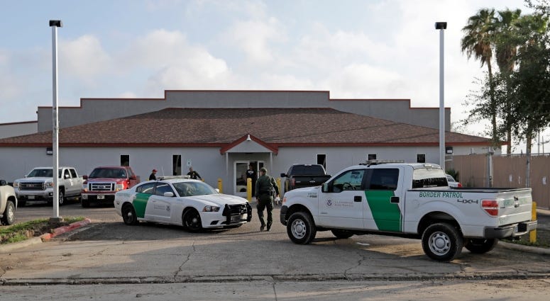 U.S. Border Patrol Agent walks between vehicles outside the Central Processing Center in McAllen, Texas