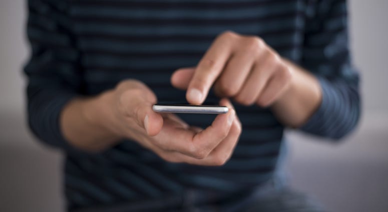 Young man using touchscreen smartphone. Concept for using technology, shopping online, using mobile apps, texting, phone addiction. Blue, media.