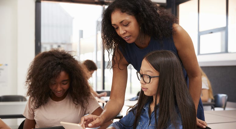 Teacher helping high school students with technology Teacher helping high school students with technology