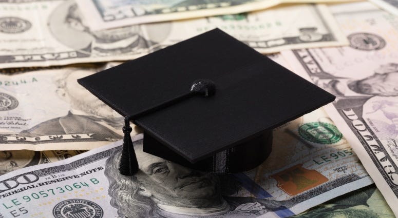 graduation cap atop dollar bills
