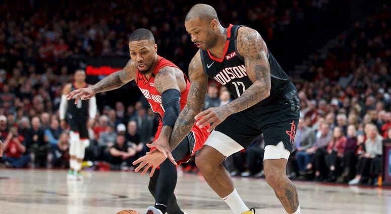 Portland Trail Blazers guard Damian Lillard (0) and Houston Rockets forward P.J. Tucker (17) reach for a loose ball during the first quarter at the Moda Center.