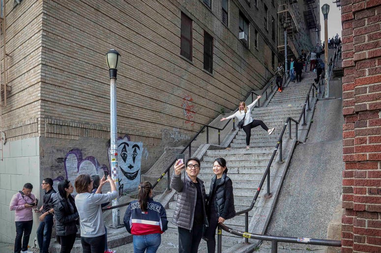 AP19301738809713 People pose on the steps between two apartment buildings, Monday Oct. 28, 2019, in the Bronx borough of New York. The stairs have become a tourist attraction in recent weeks since the release of the movie “Joker.” In the movie, lead actor Joaquin Phoenix