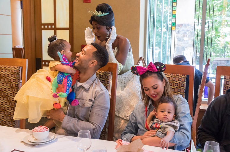 John Legend and Chrissy Teigen ANAHEIM, CALIFORNIA - APRIL 12: In this handout image, John Legend, Chrissy Teigen, their daughter Luna and son Miles share a moment with Princess Tiana during the Disney Princess Breakfast Adventures at Disney's Grand Californian Hotel on April 12, 2019