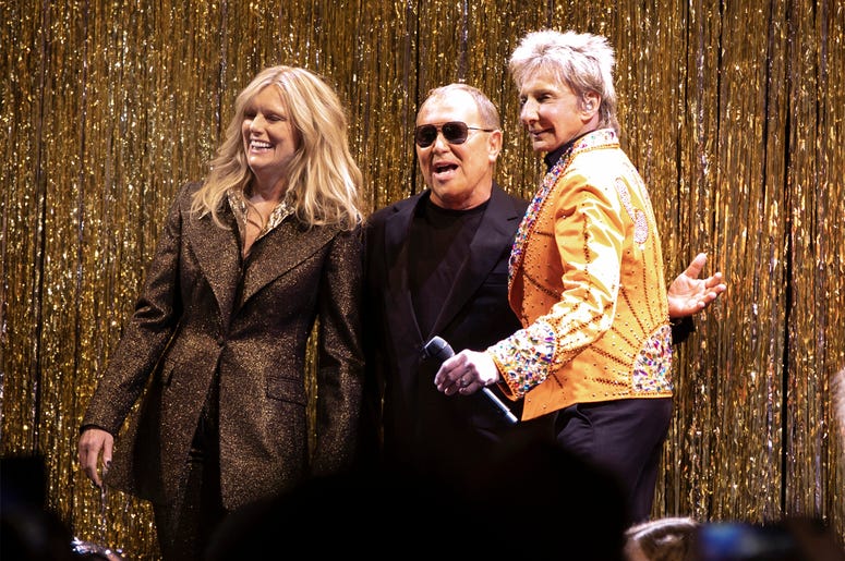 AP19044651509947 Designer Michael Kors, center, is joined by model Patti Hansen and Barry Manilow on stage after his collection was modeled during Fashion Week in New York, Wednesday, Feb. 13, 2019. (AP Photo/Richard Drew)