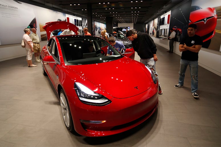 AP19070499871613 In this July 6, 2018, file photo prospective customers confer with sales associates as a Model 3 sits on display in a Tesla showroom in the Cherry Creek Mall in Denver. (AP Photo/David Zalubowski, File)