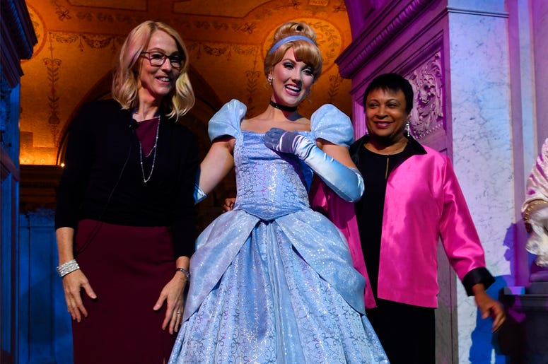 AP19172397671673 Costumed Cinderella poses with Mary Walsh, left, managing director of the Disney Animation Research Library and Librarian of Congress Carla Hayden, right, at a ceremony marking the inclusion of Disney's "Cinderella" into the National Film Registry on its