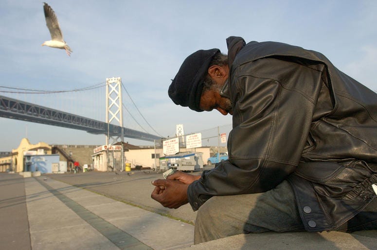 Homeless man in San Francisco SAN FRANCISCO, CA - DECEMBER 5: Maceo Grigsby, a homeless man, sits by the waterfront with the San Francisco Bay Bridge in the background December 5, 2002 in San Francisco, California. San Francisco has attracted increasing numbers of homeless people in r