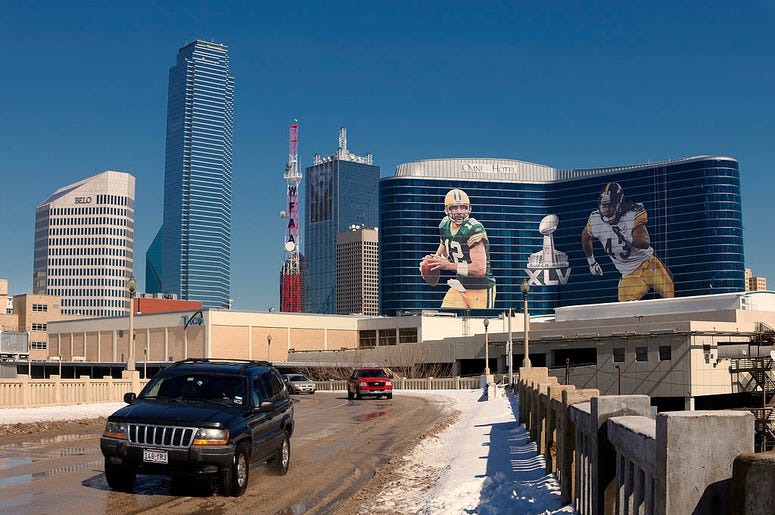 (Joe Robbins/ Getty Images) General view of the downtown skyline with Super Bowl XLV art draped from the Omni Hotel as motorists make their way along on February 5, 2011 in Dallas, Texas. The Green Bay Packers will play the Pittsburgh Steelers in Super Bowl XLV on February 6, 2011.