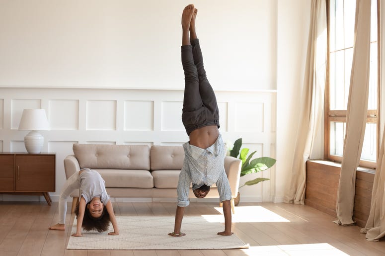 (fizkes/ iStock/ Getty Images Plus) Happy african american girl doing bridge exercise, strong father staying on hands. Smiling black family doing morning exercises together in living room at home. Daily healthy habit concept.