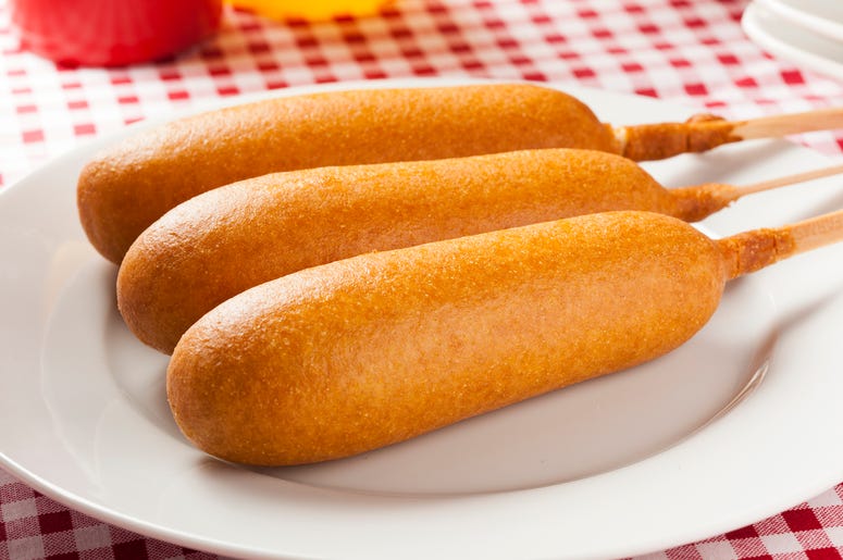 (bhofack2/ iStock/ Getty Images Plus) Corn dogs with ketchup and mustard on white background