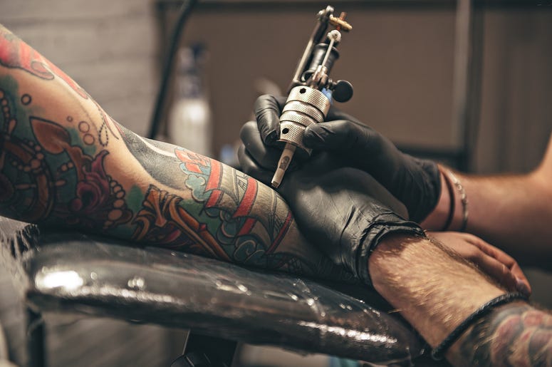 (YakobchukOlena/ iStock/ Getty Images Plus) close up tattoo machine. Man creating picture on hand with it in salon