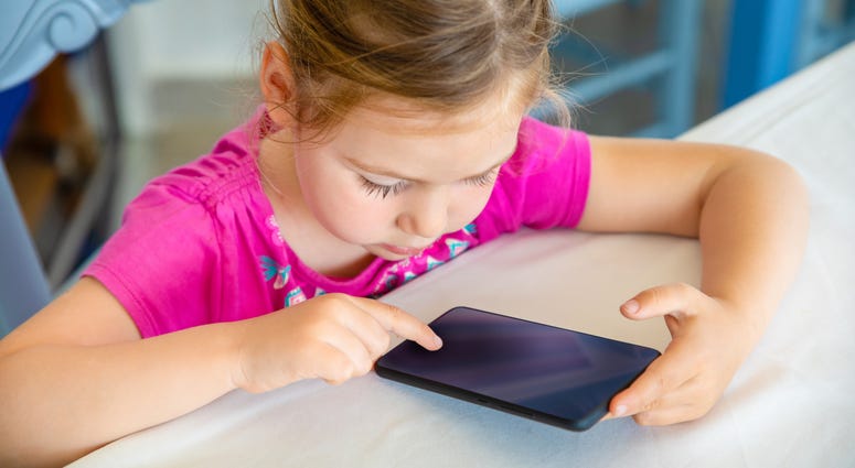Little girl uses a small touch-screen device.