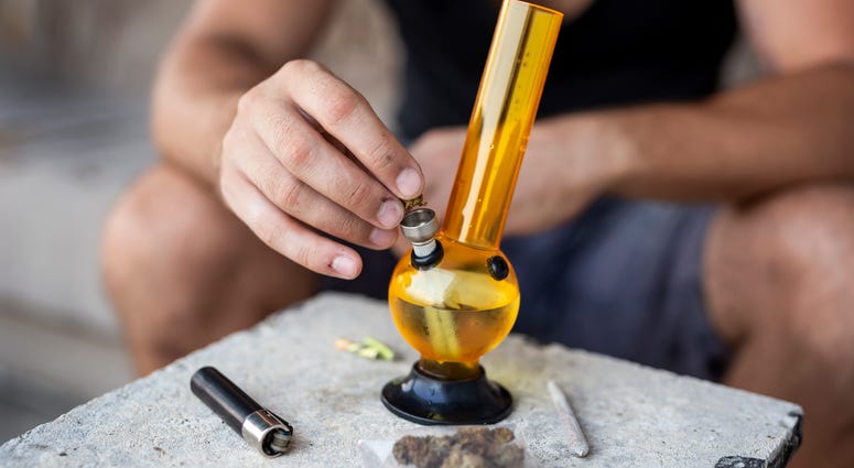 Man preparing to smoke marijuana with a water pipe