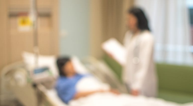 Blurry image of a doctor and a patient in a hospital room.