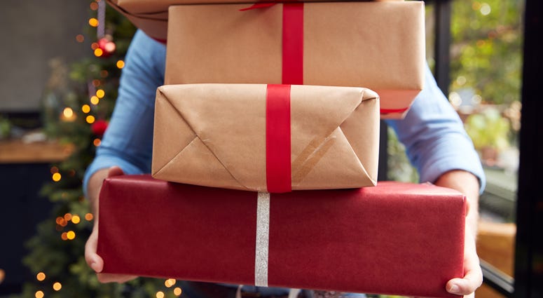 A man holds a stack of packages that obscure his face
