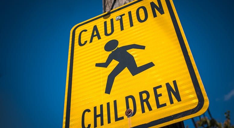 A yellow and black sign warning drivers to be cautious around children