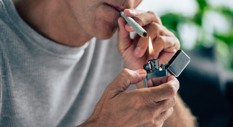 Man lighting a marijuana joint with a lighter.