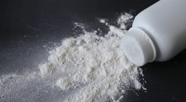 A container of talcum powder is spilled on a black background