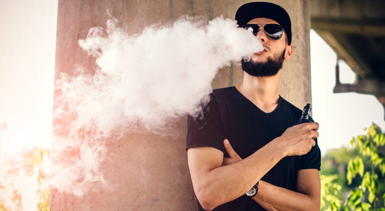 Young man blows huge cloud of steam from vaping device