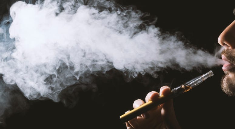 Man blows steam from an e-cigarette device