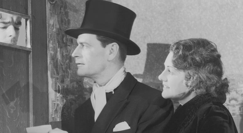 1920s man and woman stand at the door of a speakeasy bar