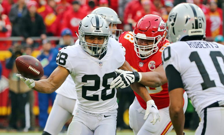 Dec 30, 2018; Kansas City, MO, USA; Oakland Raiders running back Doug Martin (28) tosses the ball to wide receiver Seth Roberts (10) as Kansas City Chiefs defensive tackle Xavier Williams (98) defends in the first half at Arrowhead Stadium. Mandatory Cred