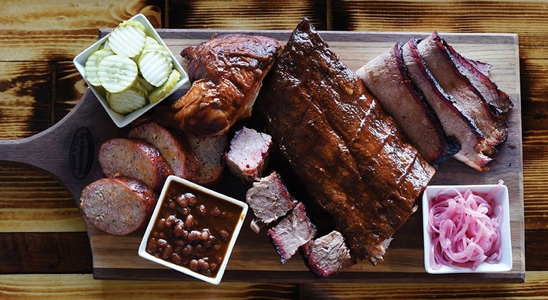 Barbecue meats and other food served on a cold cut board