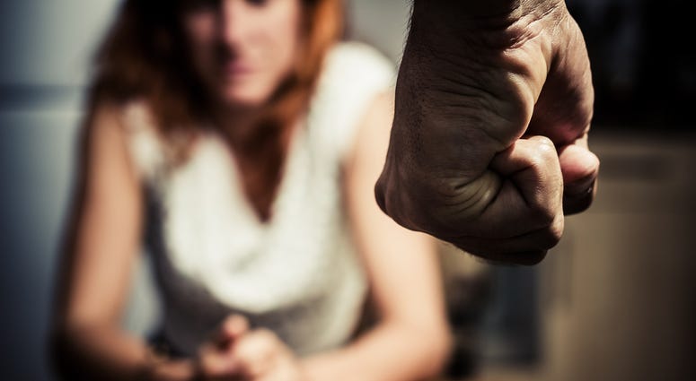 stock photo of a mans fist, a woman cowers