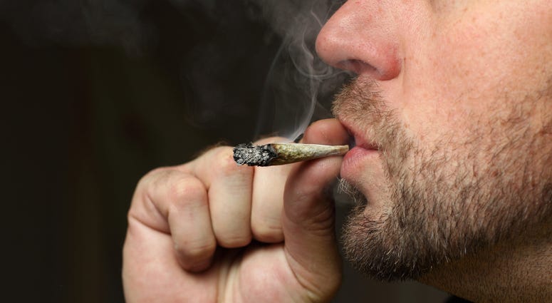 A close-up of a man smoking a marijuana cigarette joint.