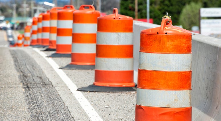 A row of orange traffic barrels lined up along a roadside
