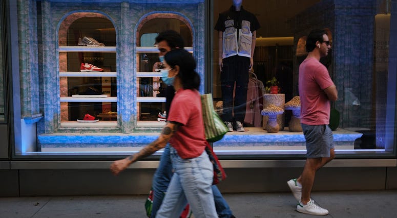 People walking on sidewalk in front of a store