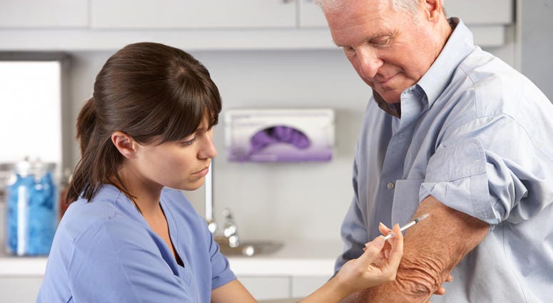 Health care worker administers flu vaccine with hypodermic needle in man's arm