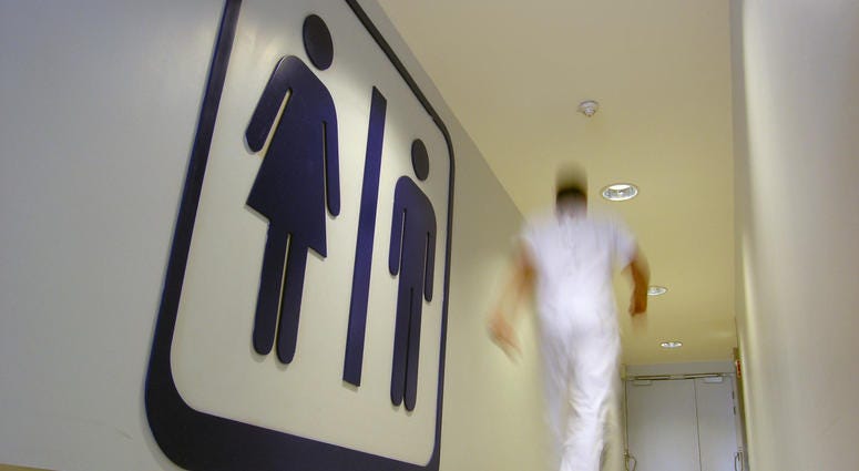 Man walking swiftly into gender-neutral public restroom