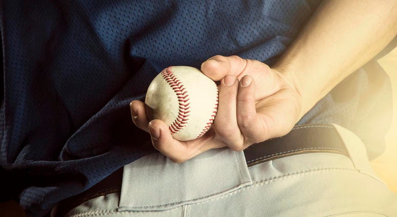Pitcher holds a baseball behind his back