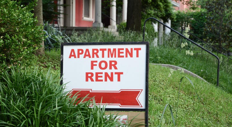 A sign in a front yard reads, "Apartment for Rent"