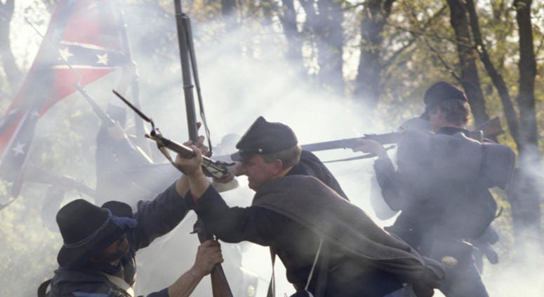 Civil War reenactors fighting with rifles and bayonets.